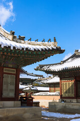 Naklejka premium Snow-Covered Korean Traditional Roofs with Japsang Figures in Winter