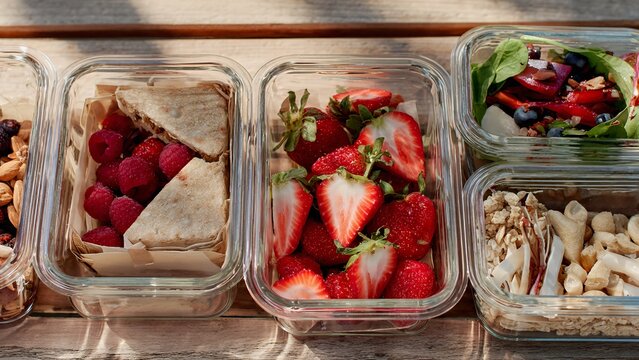 Healthy meal prep containers with fresh fruits, salad, and snacks for a balanced diet