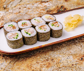 Fresh sushi rolls served on a decorative plate with ginger