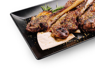 Juicy grilled lamb chops served with herbs on a black plate