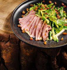 Duck salad with greens, apples, and raisins served on a rustic wooden table
