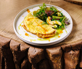 Delicious omelette served with fresh salad on natural wood table