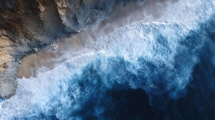 Aerial view of a rocky coastline with waves crashing onto the shore. the water is a deep blue color and the waves are white and foamy.