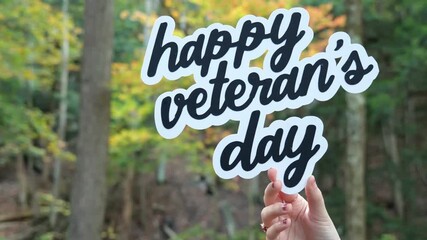 Young Woman holds up words Happy Veteran’s Day in front of Yellow and Orange Trees in the Fall Forest 4k Video Stock Footage - Powered by Adobe