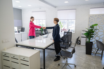 Caucasian man and woman greeting and shaking hands in office. 