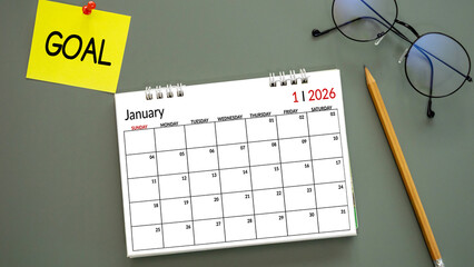 calendar of New Year 2026, January with word GOAL on post-it paper pin on green background, pencil and eyeglasses beside. symbolize New Year targets, resolutions, strategy, progress, and fresh starts