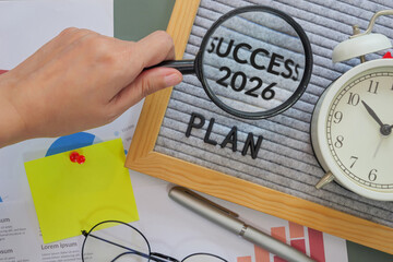 hand holding a magnifying glass points to the word Success 2026 on letter board with text plan, symbolizing fresh goals, motivation, and starts new year personal fresh planning.
