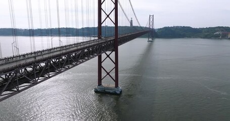 Half marathon and 10K long distance running event in Lisbon, Portugal, Europe. Runners crossing the iconic famous red 25th April suspension bridge by Cristo Rei. Drone rising