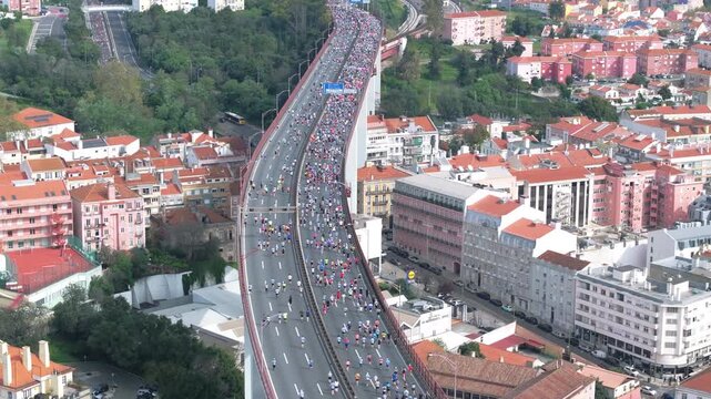 Half marathon and 10K long-distance running event in Lisbon, Portugal, Europe. Runners on the 25th April bridge running to the Águas Livres aqueduct. Alcantara, Monsanto park, aerial drone view - Powered by Adobe