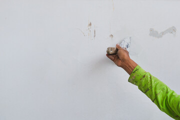 Man hand with trowel plastering a house wall outside.