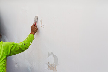 The painter scaped the wall with a trowel before painting.
