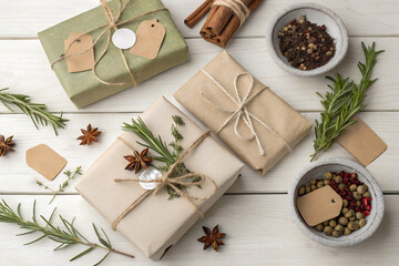 Eco-friendly holiday flat lay with kraft-wrapped gifts, herbs, star anise and spices on a white wooden surface. Warm natural styling blends Christmas mood with sustainable packaging aesthetics.