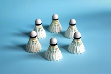 Six white badminton shuttlecocks arranged in a circle on a blue background