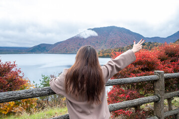 Motosuko lake, Fujikawaguchiko, Yamanashi, Japan, Woman enjoying autumn view at lake with colorful foliage and mountains