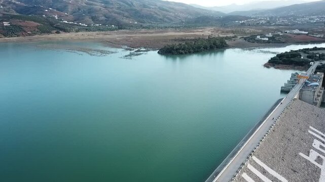 Drone footage showing a large water dam reservoir surrounded by the rugged terrain of the Rif Mountains. Hydraulic infrastructure in Morocco.