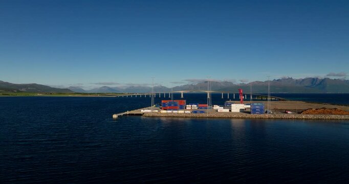 Industrial port in Stokmarknes, Norway, shipping containers on dock with Hadsel Bridge in background. Aerial drone, copy space