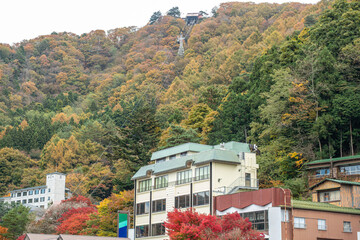 Lake Kawaguchi, Fujikawaguchiko, Minamitsuru District, Yamanashi, Japan, Buildings at the base of forested mountain with autumn foliage in rural area