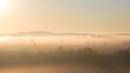 Misty golden sunrise over a distant mountain range in a hazy landscape