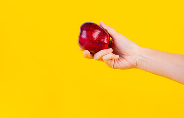 Red apple in hand yellow background