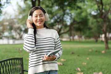Young asian woman enjoying music with headphones in park