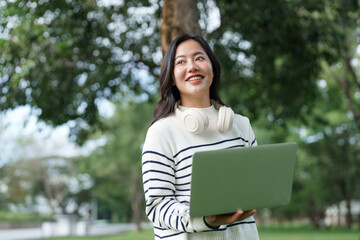 Asian woman working remotely outdoors using laptop