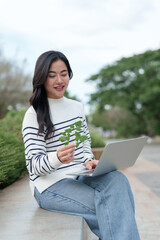 Young woman researching plants using laptop outdoors