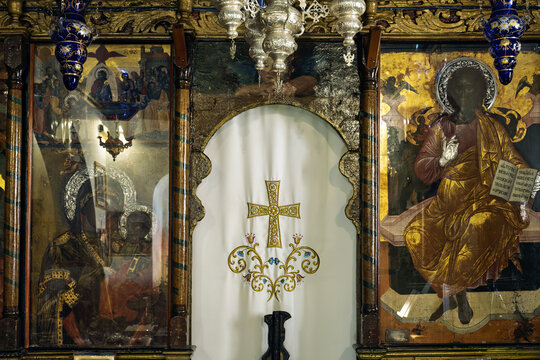 Iconostasis in Mykonos, Greece, featuring a white curtain with a gold cross and ornate floral designs at the center.