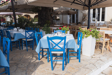 Traditional Greek taverna seating with blue chairs and tablecloths