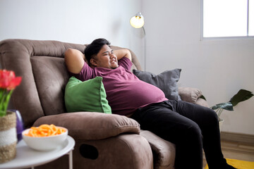 Happy Large Man Relaxing on Comfortable Sofa at Home Enjoying Free Time with Hands Behind Head