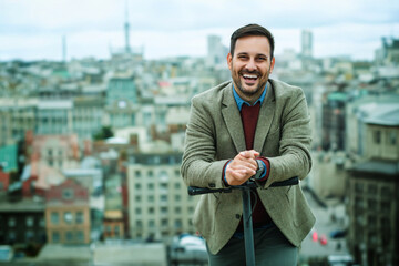 Man smiling on rooftop with city skyline in background during daytime