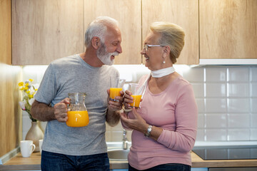 Elderly couple enjoys orange juice together in their cozy kitchen during a sunny morning