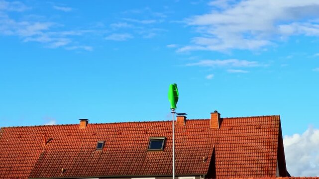 A vibrant green wind gauge captures attention against a backdrop of clear blue skies. The quaint roof adds charm to this peaceful afternoon scene, highlighting the beauty of nature.