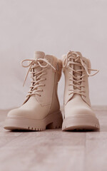 Beige trendy female boots. Fashion Shoes Still Life on the floor. Winter boots with fur with thick soles and laces. Advertising of the new collection of women's shoes. Fashion shoes