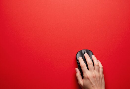 Top view photo of hand using computer mouse on isolated red background with copyspace