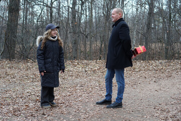 Fototapeta premium Father surprising daughter with a hidden gift in an autumn forest