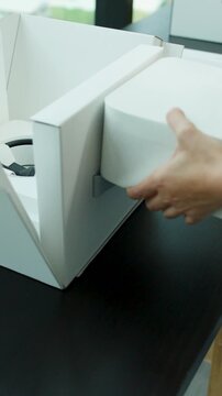 Person Unboxing Compact Desktop Computer in Modern Workspace