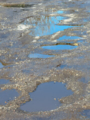 A road with puddles of water and cracks in the pavement