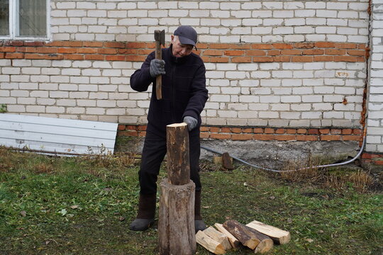 Senior man chopping firewood with an axe outdoors