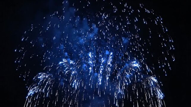 Vivid blue fireworks explode in the night sky, radiating outwards in clusters of light
