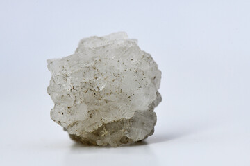 A chunk of raw, white Halite (rock salt) mineral, showing its cubic crystalline structure and translucent nature, isolated on a white background for educational or stock use.
