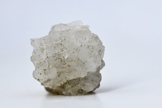 A chunk of raw, white Halite (rock salt) mineral, showing its cubic crystalline structure and translucent nature, isolated on a white background for educational or stock use.