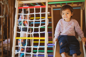 two young children play on indoor playground at home in cabin