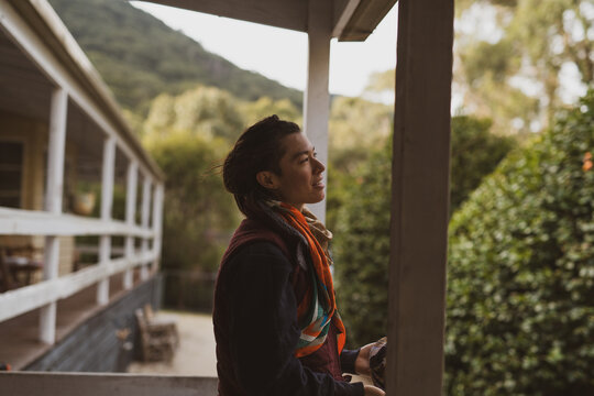 beautiful androgynous woman smiles peacefully outside home in nature