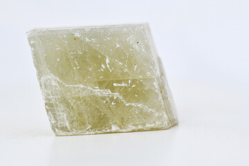 Close-up photo of a translucent, light green crystal or mineral specimen (possibly Calcite or Selenite) with natural cleavage planes, isolated on a clean white background.