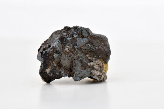 Dark, irregularly shaped raw mineral, rock specimen, ore sample, isolated on a bright white background. Image is suitable for educational, geological, and mining industry use, natural resources 