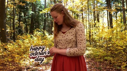 Young Woman in Golden Forest Holds Up words Happy Veteran’s Day in the Fall with Yellow Leaves 4K Video Stock Footage