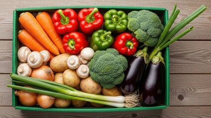 Assortment of fresh vegetables including bell peppers, broccoli, carrots, potatoes, mushrooms, onions, and eggplants in a green box on a wooden table