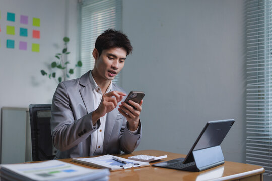 Asian businessman using mobile phone working late at office