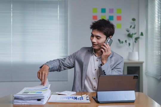 Businessman multitasking managing reports discussing financials on phone