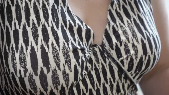 Female bust close-up in black and white dress with abstract pattern, dress that fits chest, upper part of female body dressed in dress